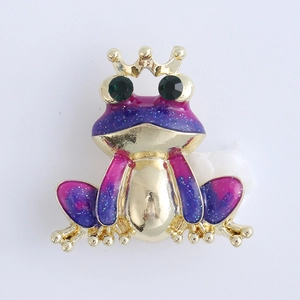 Detailed macro of a gold crown frog brooch with blue-purple gradient enamel and glitters