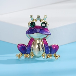 Detail of purple and blue enamel frog brooch with gold crown and green gemstone eyes