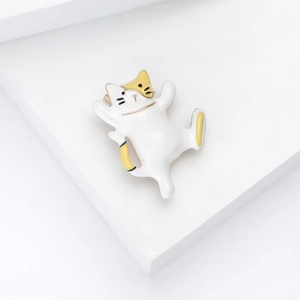 Detail view of a cute white and yellow dancing cat enamel pin on a white geometric stage