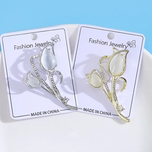 Dettaglio delle spille a tulipano oro e argento con petali di opale su carta da esposizione