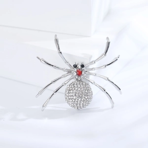 Détail de la broche araignée argentée avec strass blancs et accent en pierre rouge