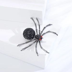 Vue détaillée de la broche araignée en strass noirs avec yeux en cristal rouge et pattes en métal