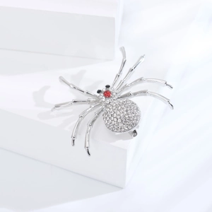 Macro de la broche araignée argentée avec strass scintillants et détails d'yeux en cristal rouge