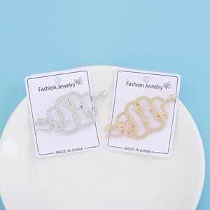 Close-up of gold and silver snake brooches with detailed scale textures on a white tray