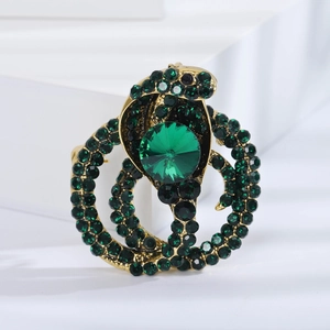 Detailed close-up of a vintage gold brooch with green rhinestones and a large faceted gem