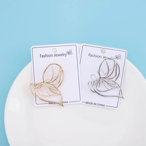 Detail of gold and silver abstract cutout face brooches on white display card