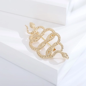 Macro detail of golden dual-headed snake brooch with intricate scale textures