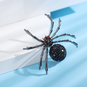 Gros plan d'une broche araignée noire avec strass brillants et yeux rouges pour costume