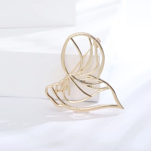 Detail of creative hollow portrait brooch with polished gold finish and pin closure