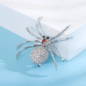 Vue détaillée d'une broche araignée argentée avec pierre rouge et strass brillants