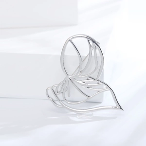 Close-up of a silver hollow abstract metal brooch on a minimalist white display