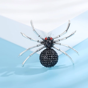 Gros plan d'une broche araignée argentée avec strass noirs et yeux en cristal rouge