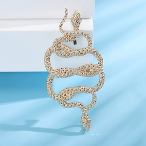 Detailed macro view of a golden snake hair clip with textured scales on a blue background