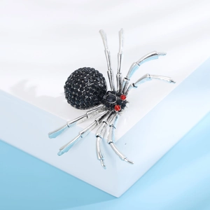 Détails d'une broche araignée argentée avec strass noirs et des petits yeux rouges