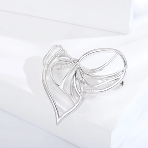 Close-up of minimalist silver hollow face brooch with modern abstract linear design