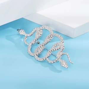 Close-up of interlocking silver snake brooch with detailed diamond-scale textures