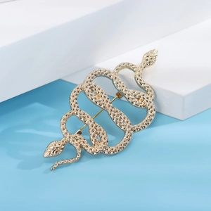 Detail of a gold snake brooch showing intricate scale texture on a geometric stand