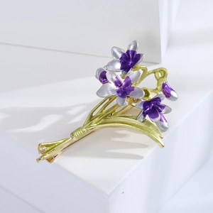 Macro detail of elegant enamel orchid brooch with purple petals and green leaves