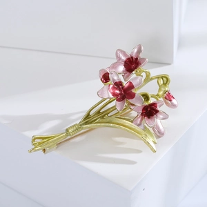 Close-up of pink enamel orchid brooch with gold-plated buds on a white block