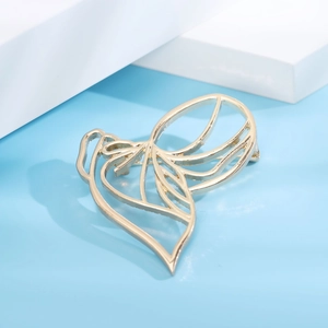 Macro shot of gold-plated abstract hollow brooch on modern geometric display stand