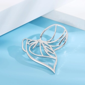 Macro shot of silver hollow abstract flower brooch with polished finish on blue background