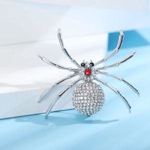 Broche araignée argentée avec strass blancs étincelants et une tête en cristal rouge vif