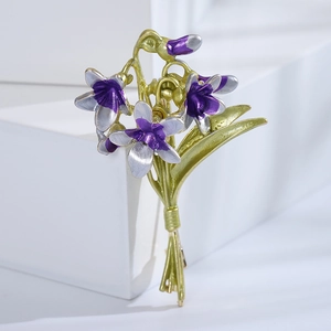 Detail of elegant enamel orchid bouquet brooch with purple petals and green leaves