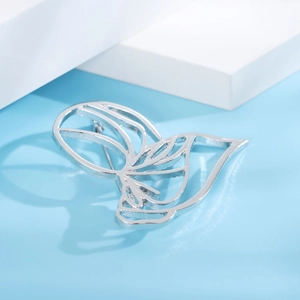 Close-up of a minimalist hollow butterfly brooch in silver plating on a blue background