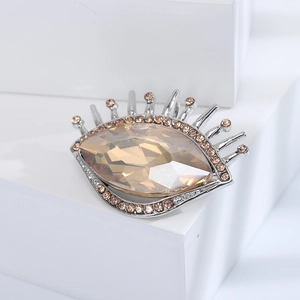 Détail macro de la broche œil argentée avec cristal champagne et cils en strass