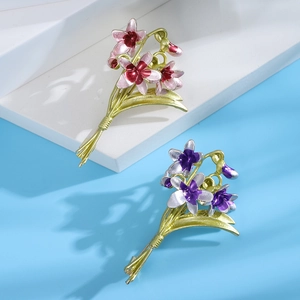 Detail view of pink and purple enamel orchid brooches with golden leaves on display