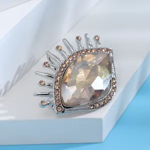 Détail d'une broche œil de luxe avec cristaux champagne sur un support blanc