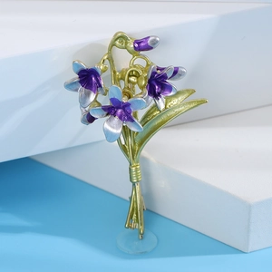Macro shot of purple enamel orchid brooch petals with gold accents on blue background