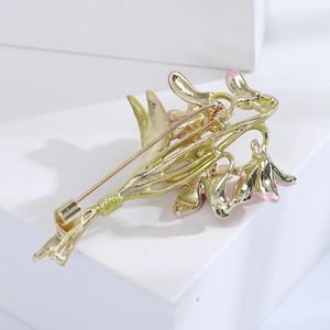 Detail view of the golden metal back and safety pin clasp of an enamel orchid brooch