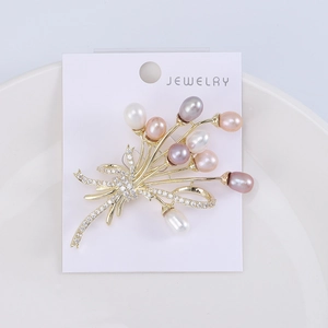 Détail d'une élégante broche bouquet dorée avec perles pastel et pierres de zircon scintillantes