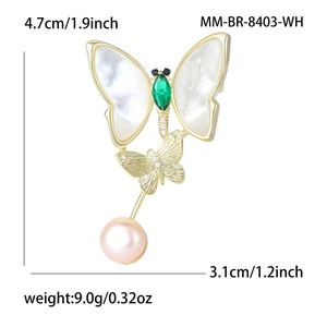 Elegant gold butterfly brooch with white shell wings, green gem, and hanging pearl detail