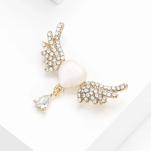 Close-up of heart cat eye stone brooch with gold wings and teardrop pendant