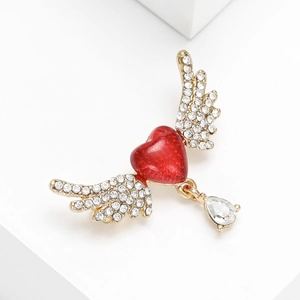 Detail view of a red heart brooch with angel wings and a pear-shaped drop pendant