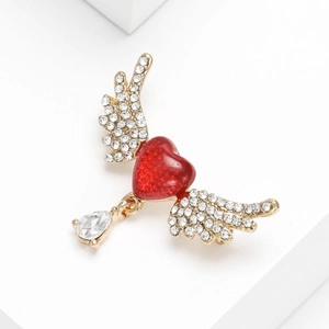 Detailed view of gold alloy heart brooch with angel wings and clear water drop gemstone