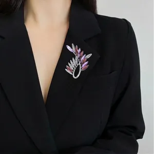 Elegant silver olive leaf brooch with purple crystals on a black suit lapel