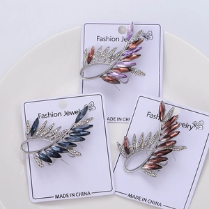 Detailed view of leaf-shaped crystal brooches in purple, blue, and brown set on display cards