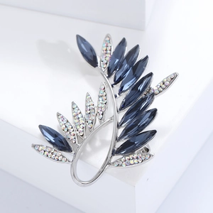Macro view of olive branch brooch with blue marquise crystals and iridescent rhinestones