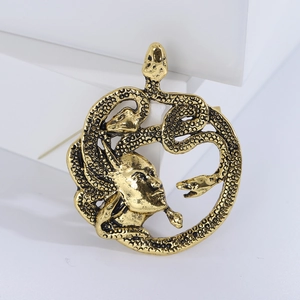 Détail de la broche Méduse dorée montrant les textures d'écailles de serpent et le relief