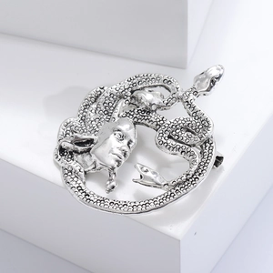 Gros plan d'une broche Méduse en argent vieilli montrant les détails des serpents et l'épingle