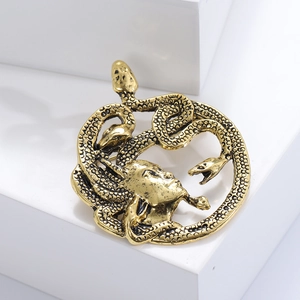 Gros plan détaillé d'une broche Méduse dorée montrant des textures de serpent et du relief