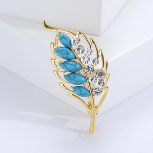 Detail of leaf brooch with turquoise stones and rhinestones on gold-plated metal