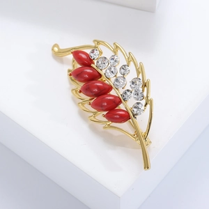 Detailed close-up of leaf brooch with gold alloy, red stones and sparkling rhinestones
