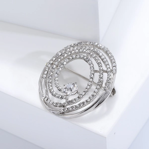Vue détaillée d'une broche spirale argentée ornée de strass pavés et d'un cristal central
