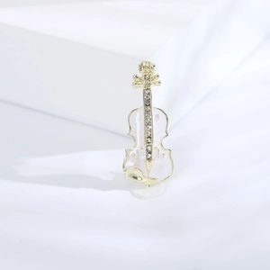 Gros plan d'une élégante broche violon dorée avec émail blanc et cristaux brillants