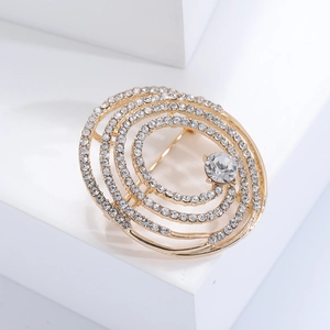 Gros plan d'une broche spirale dorée ornée de strass blancs et de gemmes brillantes