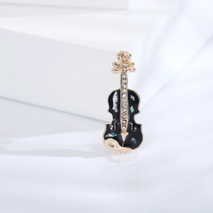 Détail d'une broche violon dorée ornée d'émail noir et de motifs nacrés brillants